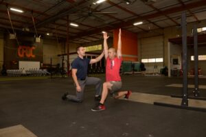 Doctor of chiropractic coaching a patient through an overhead reverse lunge movement screen