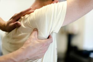 Close-up of a clinician performing hands-on shoulder soft tissue therapy on a patient